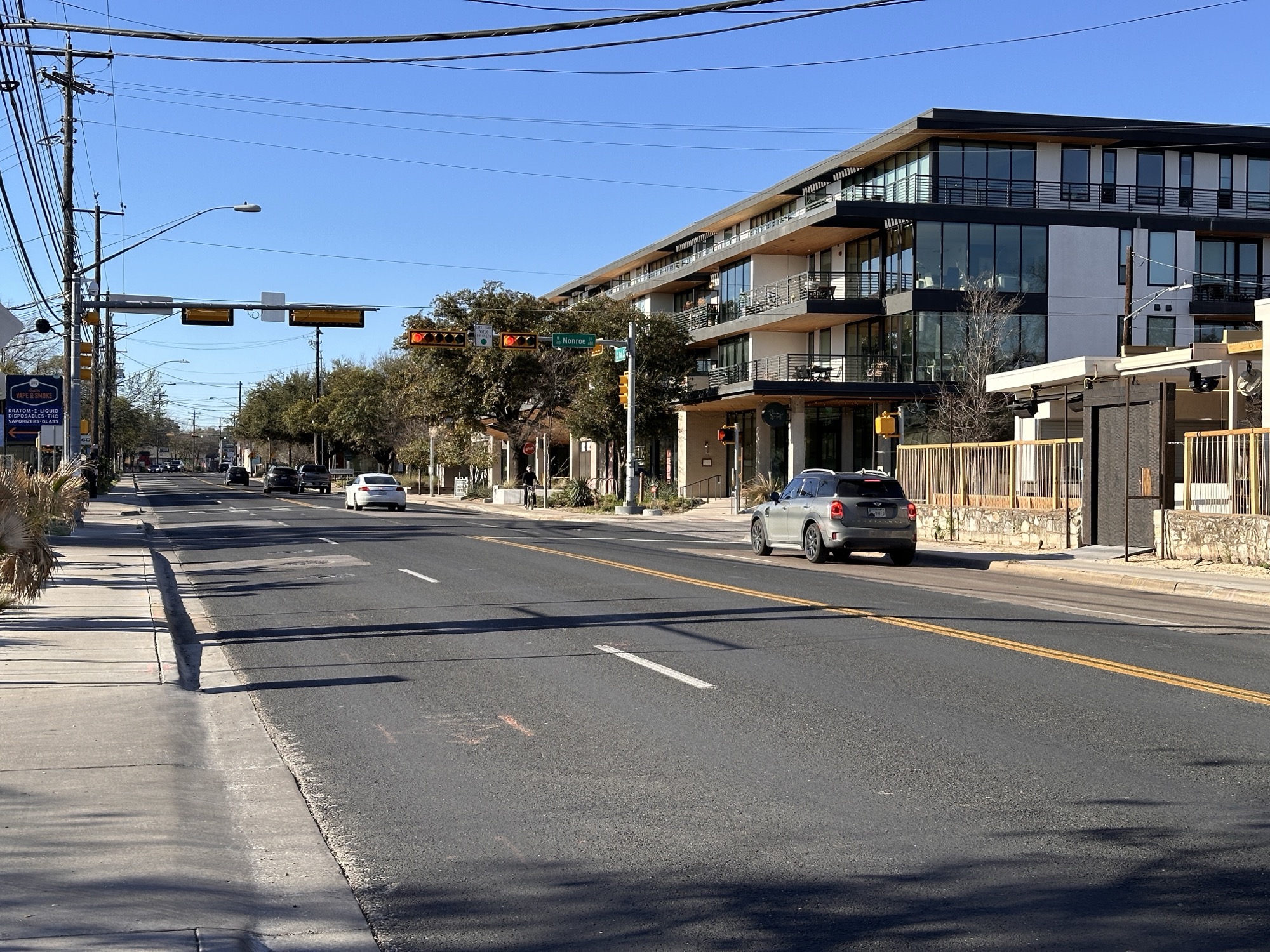South First Street at Monroe, showing four travel lanes, storefronts, traffic signals, and narrow sidewalk edges